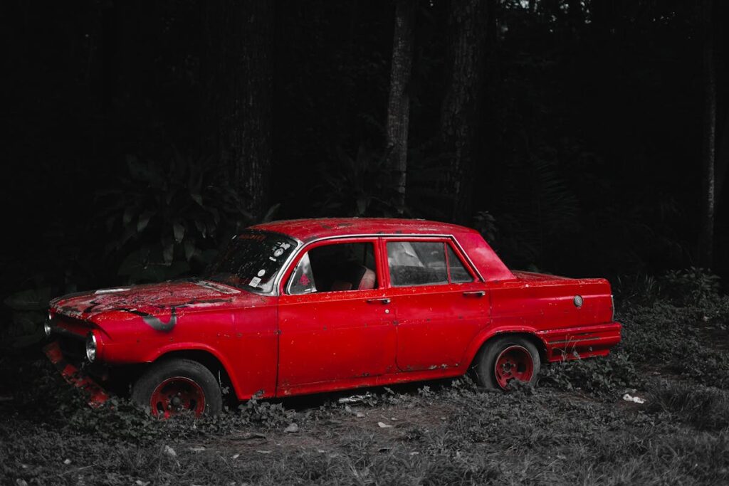 Old fashioned red car left in woods