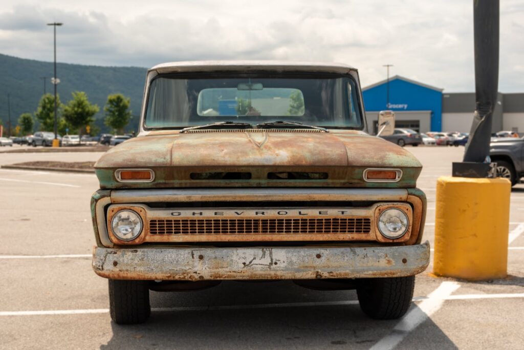 Front view of a vintage rusty Chevrolet truck parked outdoors.