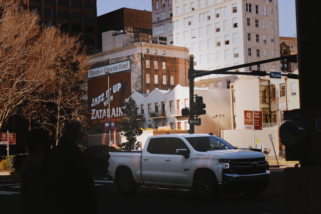 Side view of a parked white pickup truck on a New Orleans street during the day.